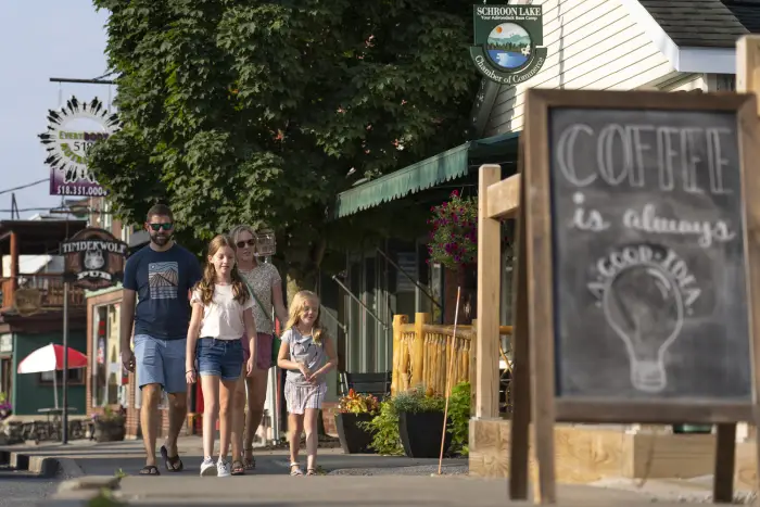 A family of four walks down a sidewalk in the middle of town.
