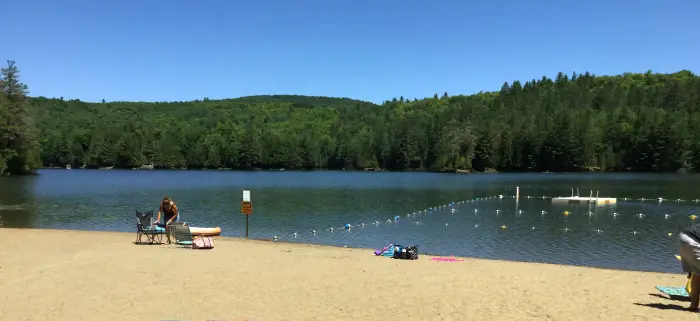 A white beach on the shore of a lake with ropes to guard off swimming.
