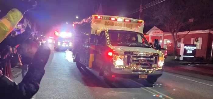 An emergency vehicle decorated with holiday lights drives down a Schroon Lake street at nighttime