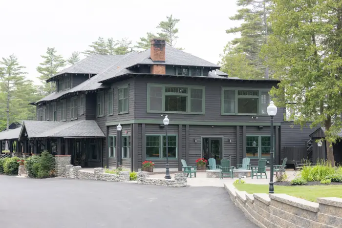 The side of a black lodge with stone patio.