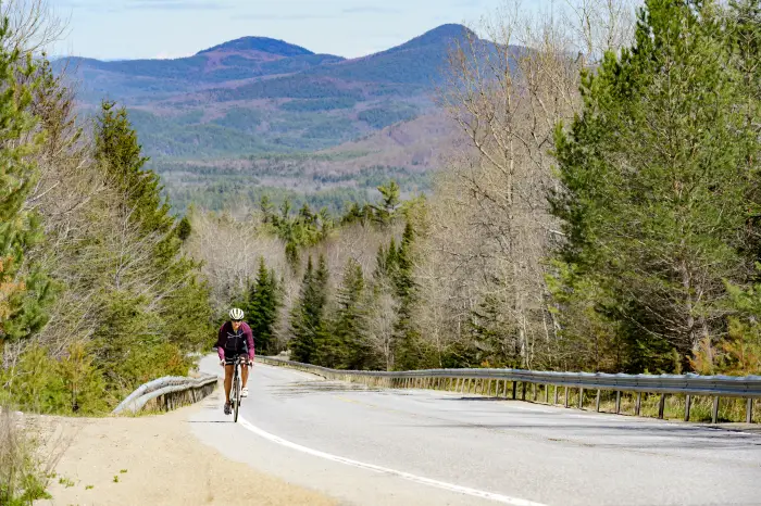 A cyclist rides Blue Ridge Road with the Adirondack Mountains in the background.