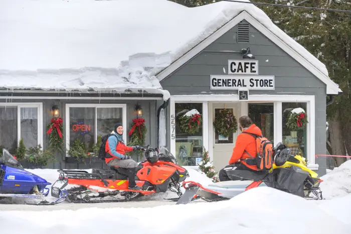 A few snowmobilers and their machines outside a cafe