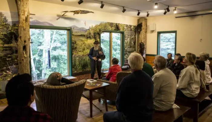 A group of people sit indoors and listen to a naturalist talk